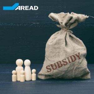 figurines en bois de petits hommes d'une famille et d'un sac plein avec l'inscription subvention sur fond bleu. Cette image a pour le but de représenter les subventions pme en France en 2025