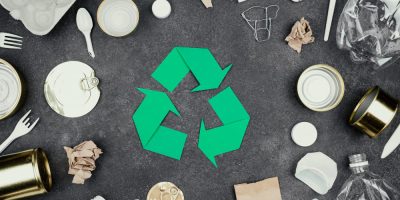 Symbole du recyclage entouré d’emballages plastiques et métalliques, illustrant les aides ADEME pour le réemploi des emballages et l’économie circulaire