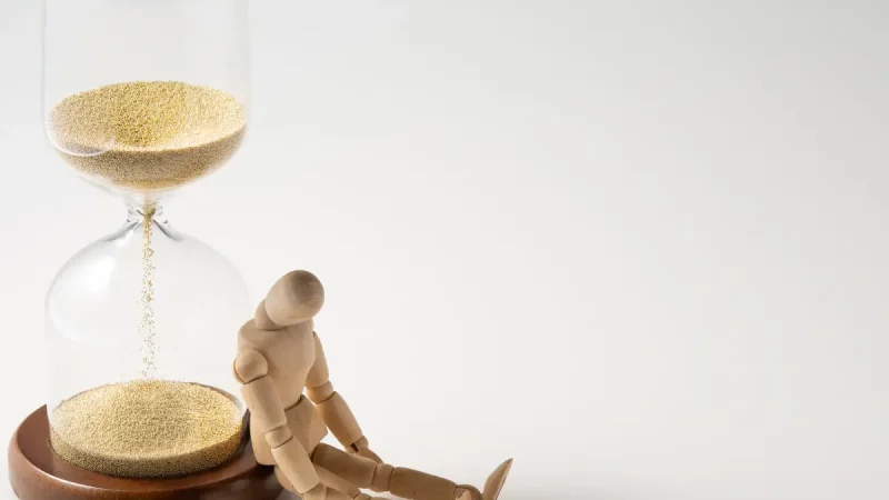 Le sablier et la figurine d'homme illustrent l'impact du temps sur le PLF 2025