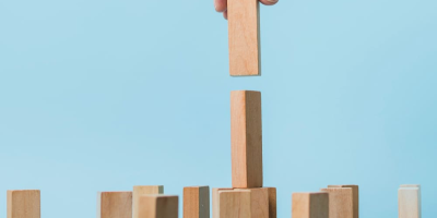 figurines en bois de petits hommes d'une famille et d'un sac plein avec l'inscription subvention sur fond bleu. Cette image a pour le but de représenter les subventions pme en France en 2025