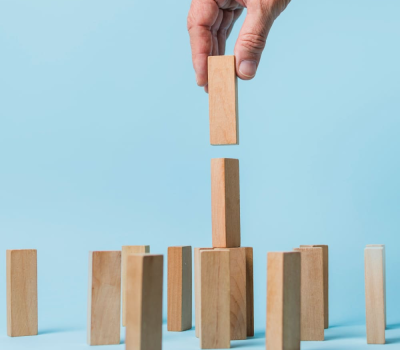figurines en bois de petits hommes d'une famille et d'un sac plein avec l'inscription subvention sur fond bleu. Cette image a pour le but de représenter les subventions pme en France en 2025