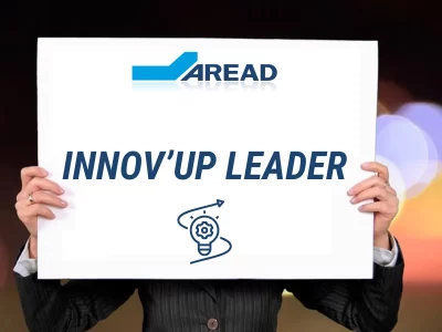 Une personne tenant une feuille blanche sur laquelle figurent les mots « Innov'up leader » et le logo d'Aread.